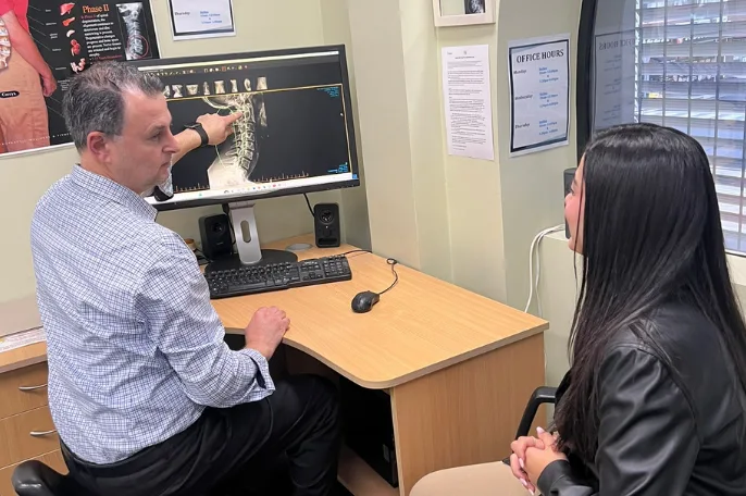 Chiropractor reviewing a spinal X-ray with a patient at the practice