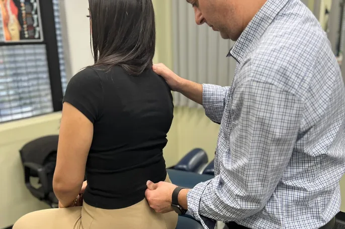 Chiropractor examining a patient's lower back at the practice