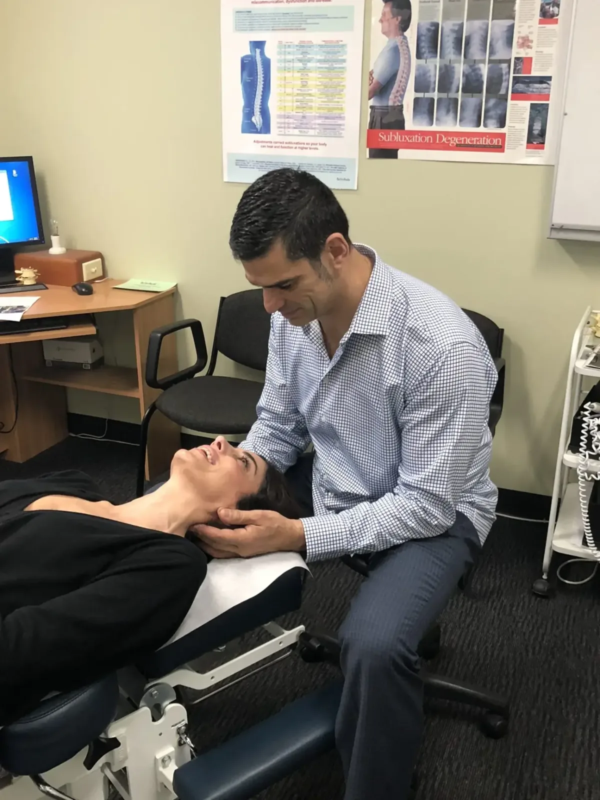 Dr Stelios Matsis examining a patient's neck in a treatment room