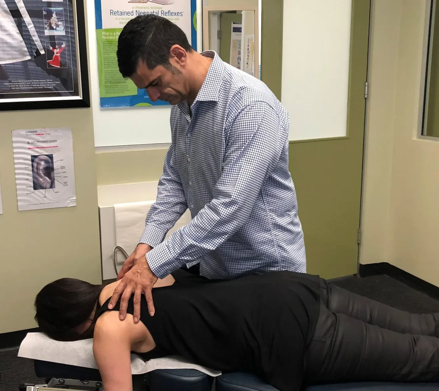 Dr Stelios Matsis examining a patient's upper back in a treatment room