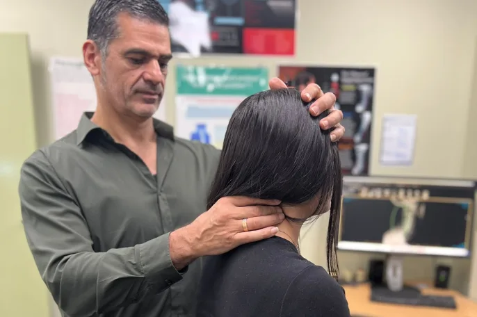 Chiropractor examining a patient's neck at the practice