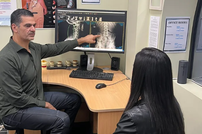 Chiropractor explaining a lower back X-ray to a patient at the practice